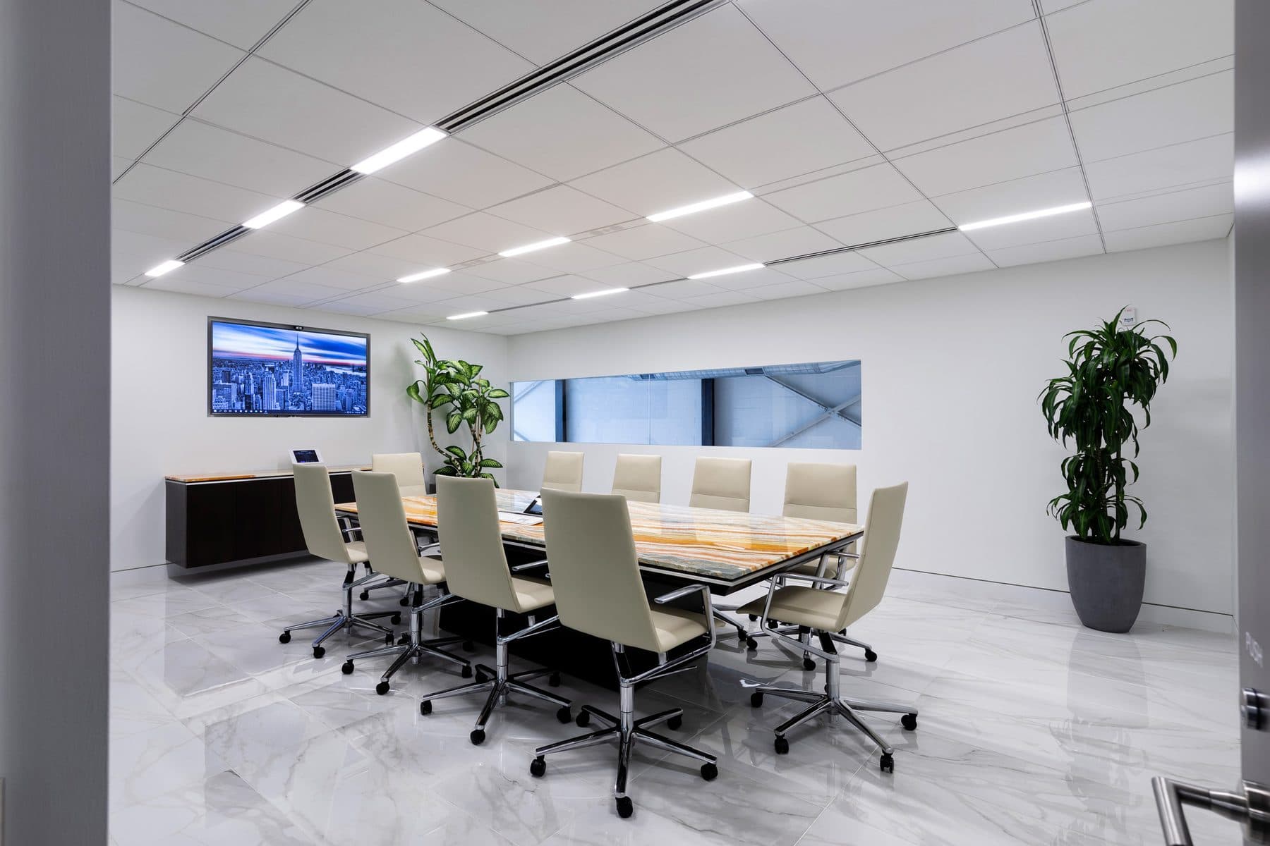 A conference room with a long table and a display at the far end